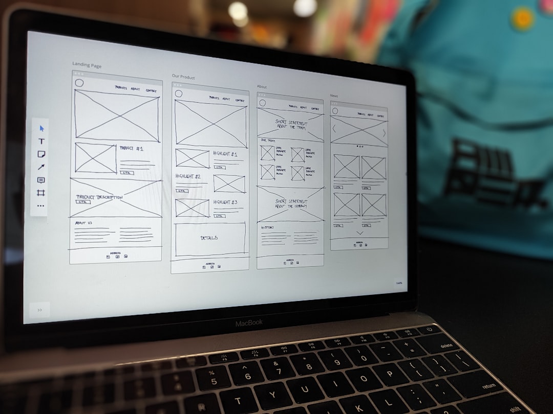 A website wireframe shown on a MacBook screen, placed on an office desk.